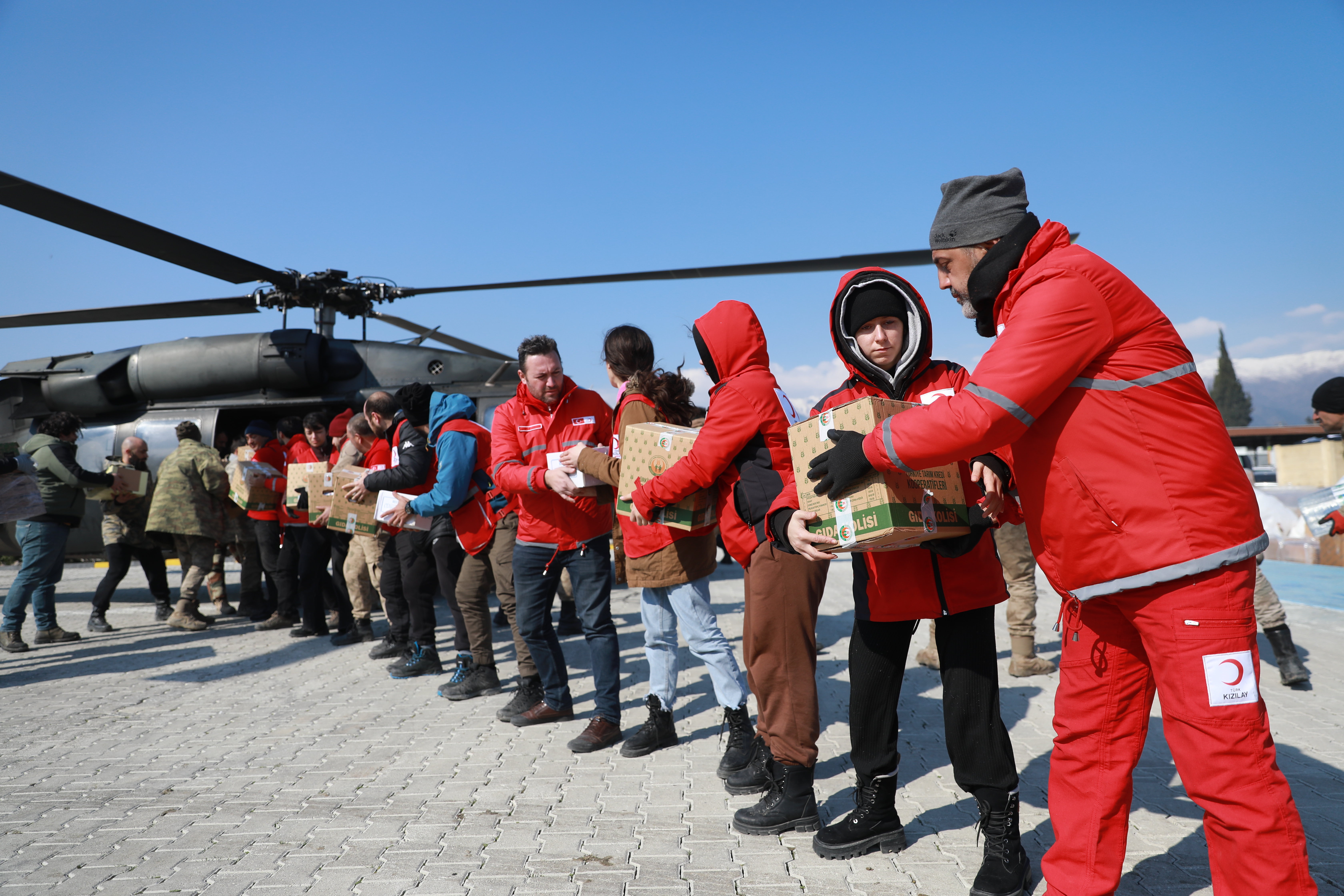 A line of people passing along items from a helicopter