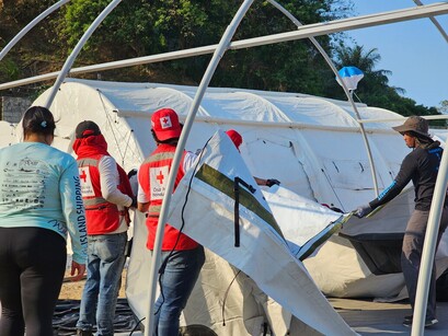 A group of people in Red Cross vests setting up a tent