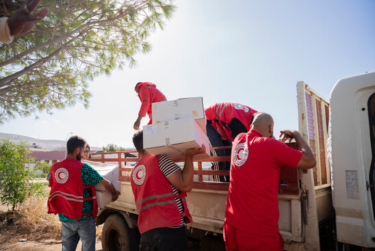 A group of people in Red Crescent attire unload items from a truck